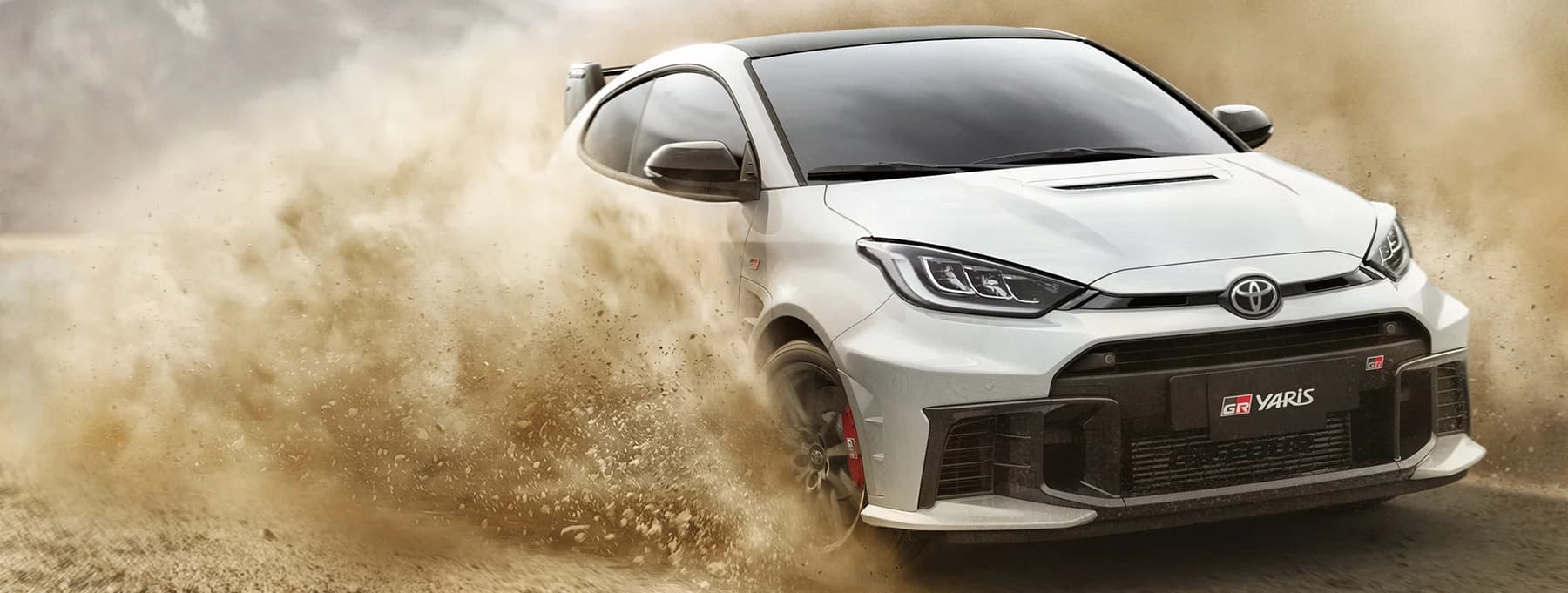 A sports car driving through a cloud of dust